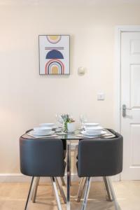 una mesa de comedor con sillas negras y una pintura en Apartment 10, en Worksop