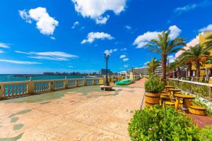a walkway next to the beach with tables and chairs at 宮城海岸徒歩2分 大人も子供もBBQや子供用プールで楽しめる　アメリカンビンテージのデザイナーズハウス in Chatan