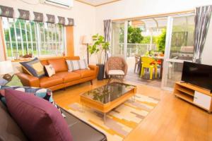 a living room with a couch and a table at 宮城海岸徒歩2分 大人も子供もBBQや子供用プールで楽しめる　アメリカンビンテージのデザイナーズハウス in Chatan