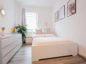 une chambre blanche avec un lit et une commode dans l'établissement EUPHORAS - Modern eingerichtete Ferienwohnung mit 3 Schlafzimmern im Harz, à Clausthal-Zellerfeld