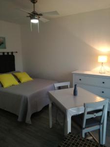 Un dormitorio con una cama con almohadas amarillas y una mesa. en Le Provence, en Gréoux-les-Bains