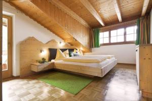 - une chambre avec un grand lit dans une pièce dotée de plafonds en bois dans l'établissement Appartamenti Pastüres, à Colfosco