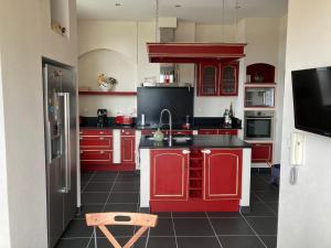 cocina con armarios rojos y encimera negra en Belle maison de famille en Usson-en-Forez