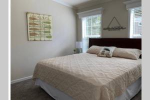 a bedroom with a large bed and two windows at Resort Cottage near parks at Great Price! in Kissimmee