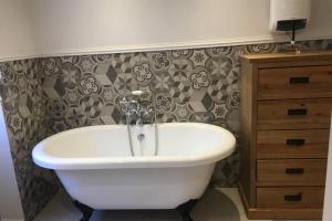 a bathroom with a white bath tub next to a dresser at La Maison du Rempart in Eguisheim
