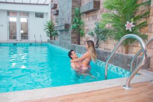 a man and woman sitting in a swimming pool at Hotel Royal Inn in Tacna