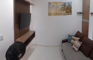a living room with a couch and a flat screen tv at Temporada de frente para o mar in Caraguatatuba