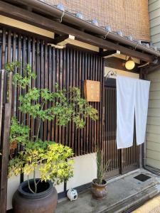 une serviette est suspendue sur une clôture avec deux plantes dans l'établissement Machiya Kikunoya, à Nagoya