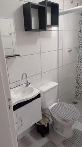 La salle de bains blanche est pourvue d'un lavabo et de toilettes. dans l'établissement Temporada de frente para o mar, à Caraguatatuba