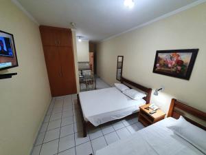 a hotel room with two beds and a tv at JF Flat - Hotel in Ribeirão Preto