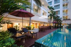 uma piscina exterior com cadeiras e um guarda-sol e um hotel em AT EASE saladaeng by AETAS em Banguecoque