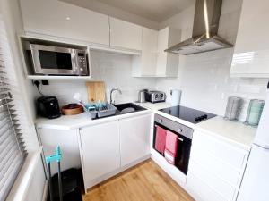 a white kitchen with a sink and a microwave at Bournemouth Luxury Apartment in Bournemouth