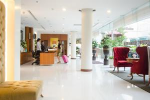 a lobby with red chairs and people in a building at AT EASE saladaeng by AETAS in Bangkok