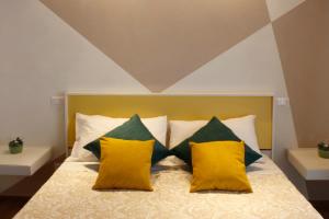 Una cama con almohadas amarillas y verdes. en B&B LE MUSE, en Barletta