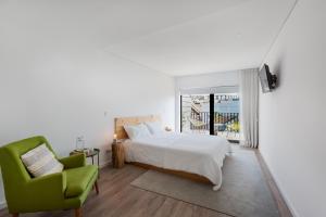 Autor Guesthouse في فيلا دو كوندي: غرفة نوم بسرير وكرسي أخضر