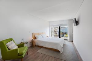 a bedroom with a bed and a green chair at Autor Guesthouse in Vila do Conde