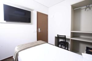 een kamer met een bed en een flatscreen-tv bij Hotel Pro Tork Confort in Santo Antônio da Platina