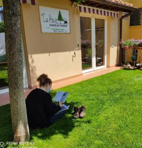 una mujer sentada bajo un árbol leyendo un libro en B&B "La Pieve" - Locanda per Viandanti, en San Piero a Sieve