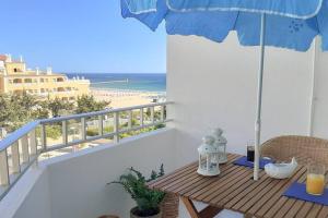 uma mesa com um guarda-sol numa varanda com praia em Cozy beach front apartment em Portimão