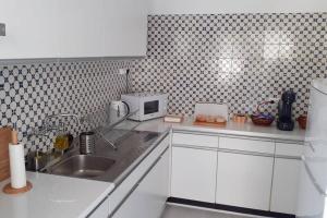a white kitchen with a sink and a microwave at Cozy beach front apartment in Portimão