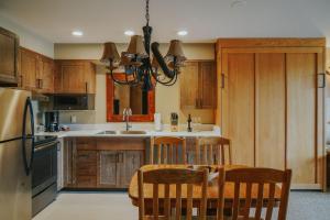 a kitchen with wooden cabinets and a table and chairs at Shoshone Condos at Big Sky Resort in Big Sky