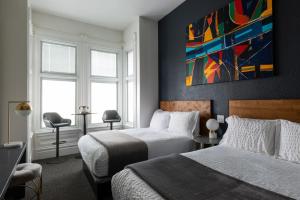 a bedroom with two beds and a painting on the wall at The Metro Hotel in San Francisco