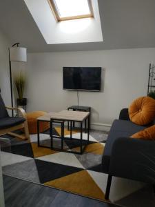 ein Wohnzimmer mit einem TV, einem Sofa und einem Tisch in der Unterkunft Tosca - Appartement - Parking gratuit in Orléans