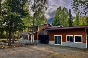 a house with a garage in the woods at Peaceful Mountain-View Home - Walk to Kenai Lake! in Cooper Landing