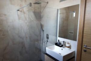 ein Badezimmer mit Waschbecken und Dusche mit Spiegel in der Unterkunft SNP city center lux in Novi Sad + 10 Fotos