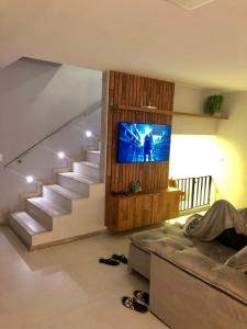 sala de estar con sofá, TV y escaleras en Chalé lindo para toda família nas montanhas !!!, en Domingos Martins