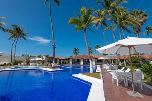 巴拉德纳维达Cabo Blanco Hotel and Marina的一个带椅子和遮阳伞的游泳池,并种植了棕榈树