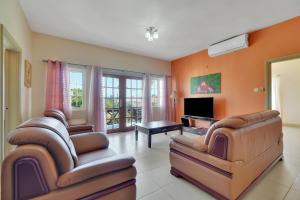 a living room with two chairs and a television at Mandela Court Suites Grenada in Lance aux Épines