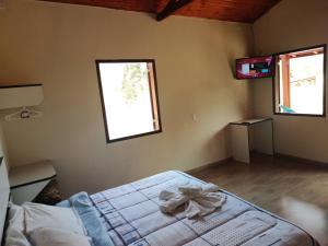 a bedroom with a bed and a television in it at Chalé caminho das cachoeiras in São Thomé das Letras