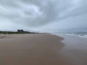 an empty beach with a castle in the distance at Brada View Bamburgh in Bamburgh