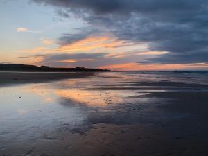 a sunset on a beach with a cloudy sky at Brada View Bamburgh in Bamburgh