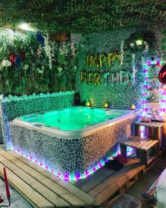 Jungle Vibes - Jacuzzi - Sauna في Yerres: حوض جاكوزي في حديقة مع علامة عيد ميلاد سعيد