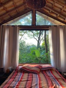 uma cama num quarto com uma grande janela em Chalé Rústico - Retiro Andaluz em Moeda