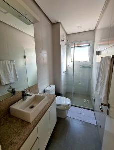 a bathroom with a sink and a toilet and a shower at Loft Gramado in Gramado
