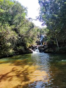 a river with a waterfall in the middle of a forest at Chalé caminho das cachoeiras in São Thomé das Letras +17 photos