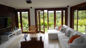 a living room with a white couch and a tv at Casa Praia do Forte - Piscinas naturais in Farol