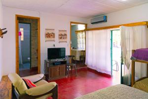 una sala de estar con TV y una habitación con sofá en La Casa de Don Pepe en Villa Las Rosas