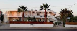 a large white building with palm trees in front of it at River's Apartments in Rhodes Town