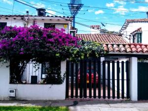 una casa blanca con flores púrpuras en una valla en Casa Turística Camitas Inn en Bogotá