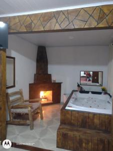 a living room with a fireplace and a bed and a chair at Chale brilho do sol in Visconde De Maua