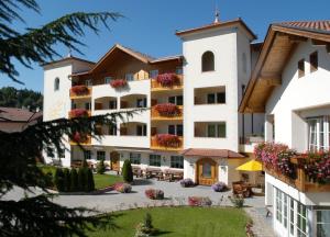 a large white building with a courtyard at Hotel Sonnenhof in Castelrotto