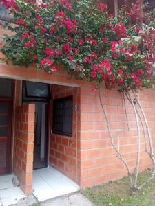 un bâtiment en briques avec une plante ornée de fleurs roses dans l'établissement Condomínio Ville I, à Ubatuba