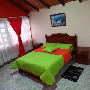 1 dormitorio con 1 cama con sábanas verdes y rojas en Hospedaje Villa Isabel, en Aquitania