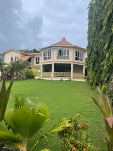 Casa grande con patio grande con césped verde en Mandela Court Suites Grenada en Lance aux Épines