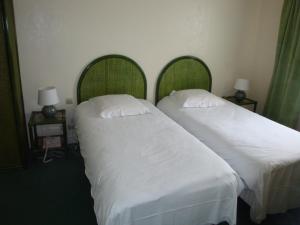 two beds in a hotel room with white sheets and pillows at Hôtel de l'Orme, Akena in Évreux
