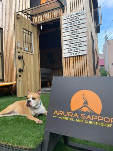 a dog laying on the grass in front of a sign at Arura Sapporo in Sapporo